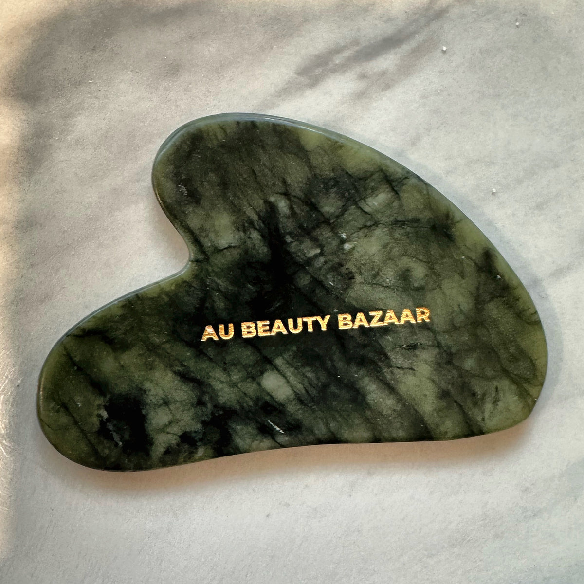 AU Beauty Bazaar heart-shaped green jade gua sha with gold logo