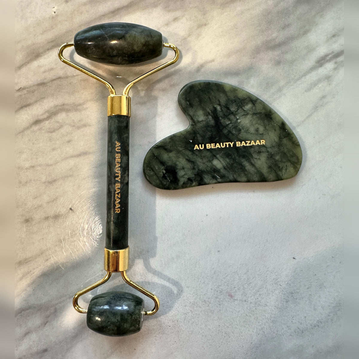 AU Beauty Bazaar jade roller and gua sha set, flat lay on marble